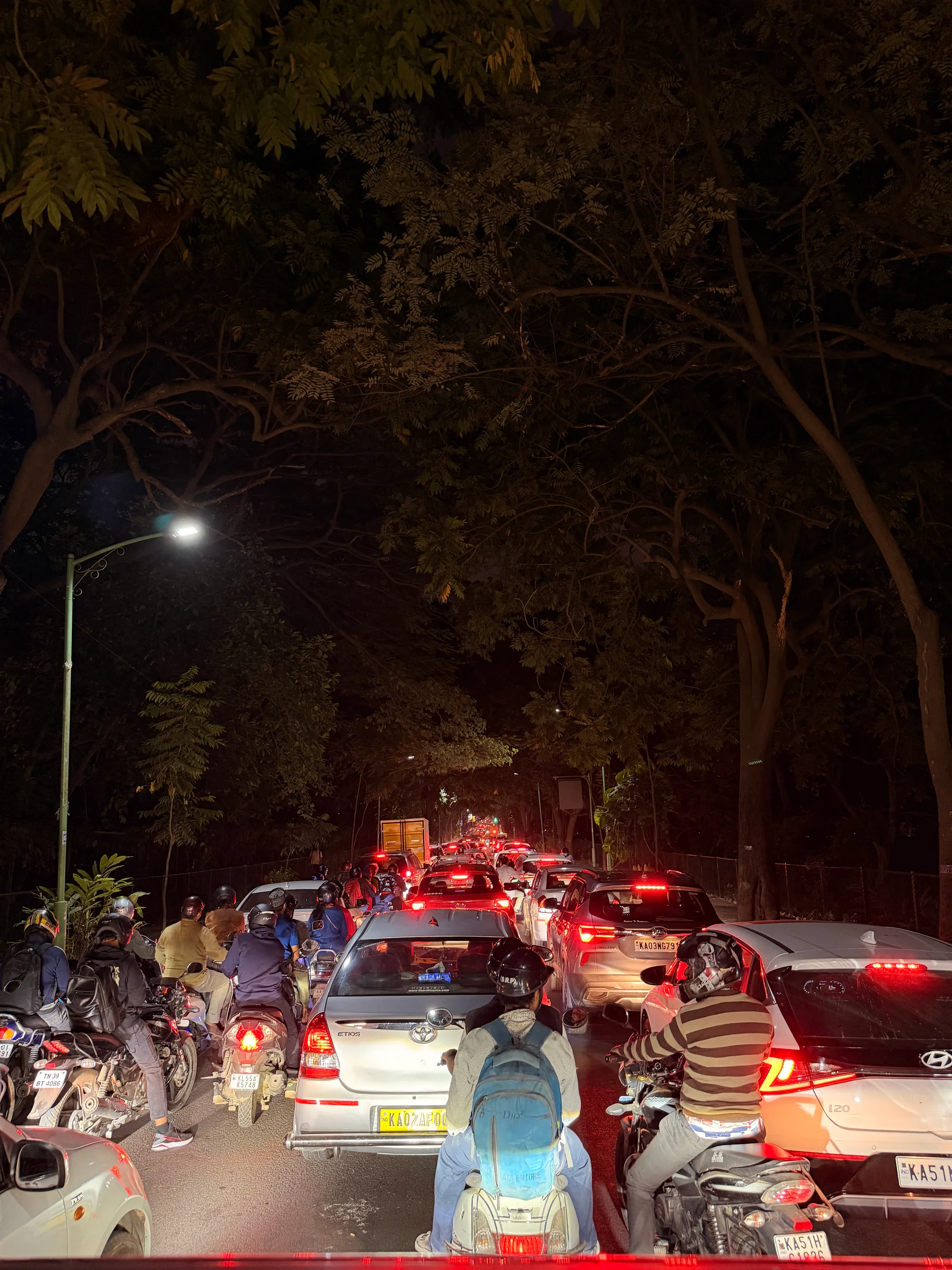 An LED streetlight glowing weakly against a dim street, barely pushing any light onto the road below